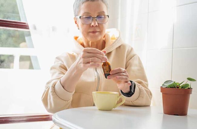 person reading a CBD oil bottle with cup of tea