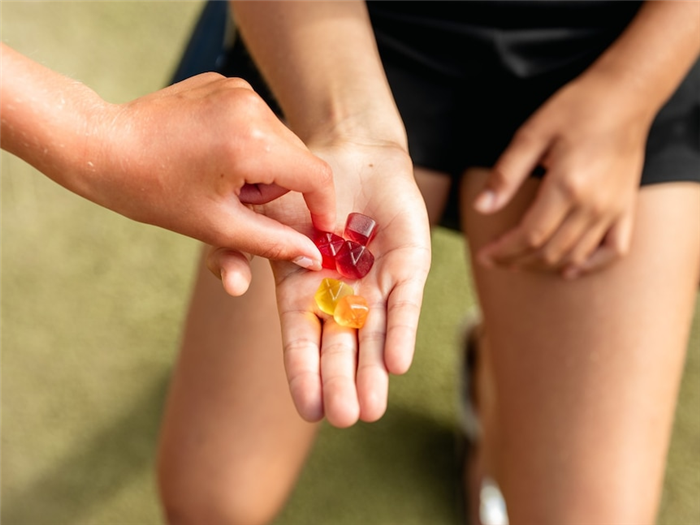 A person offers a handful of gummy lollies to another