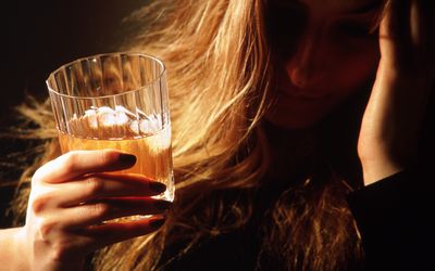 Depressed woman drinking a glass of beer