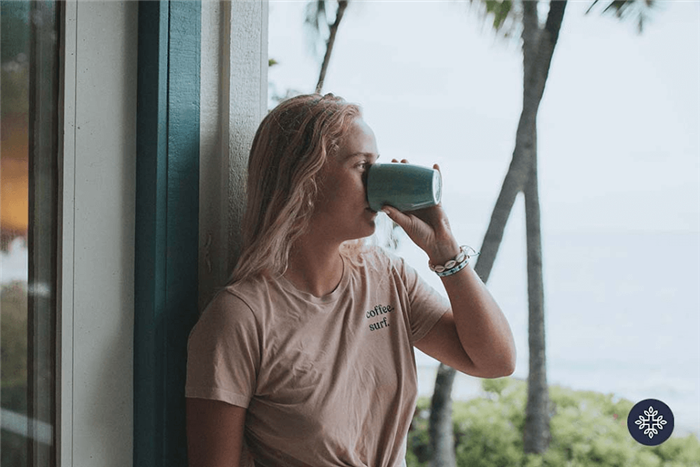 Woman with blonde hair drinking CBD tea and overlooking the ocean