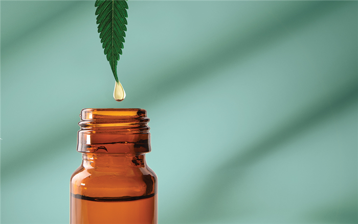 Green leaf drips cannabis oil into brown bottle.